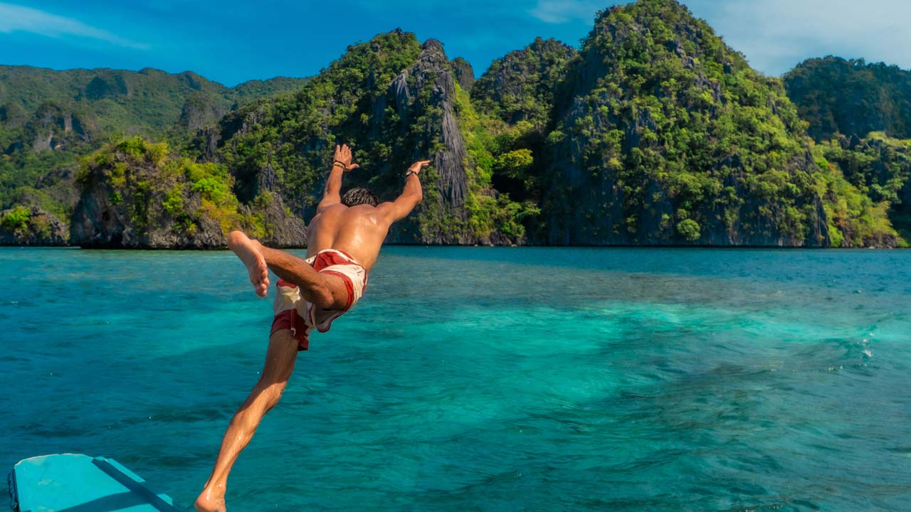 Man jumping clear blue water in Coron